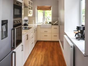 cocina con armarios blancos y suelo de madera en 8 Stratford Villas, en Ferryside