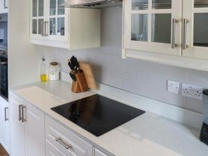 una cocina con armarios blancos y fregadero negro en 8 Stratford Villas, en Ferryside 12 fotos más