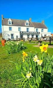 a large white building with flowers in front of it at Manor House Hotel Holy Island in Berwick-Upon-Tweed