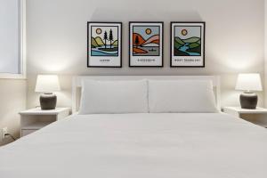 ein weißes Bett mit vier Bildern an der Wand in der Unterkunft Slopeside Ski In Ski Out Second Floor Condo in Blue Mountains