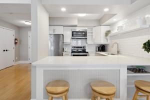 eine Küche mit weißen Arbeitsplatten und Holzhockern in der Unterkunft Slopeside Ski In Ski Out Second Floor Condo in Blue Mountains