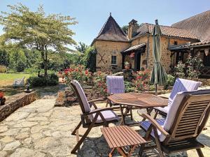 Un patio con sillas, una mesa y una sombrilla. en Restored Farmhouse for10 persons with Pool & Airco, en Doissat