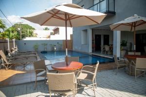 eine Terrasse mit Tisch und Stühlen und einem Sonnenschirm in der Unterkunft Apto Vista Mar Jogos Piscina 2 Suítes in São Bento
