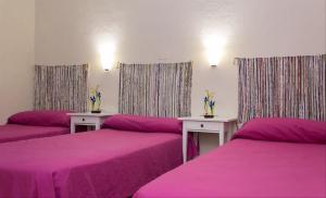 塞维利亚金橙花旅馆的带3张床和粉红色床单及桌子的房间