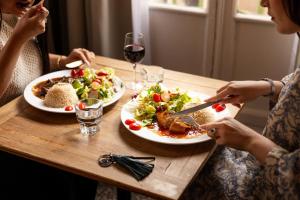 two women sitting at a table with plates of food at Hôtel Le Relais de Poste Arles Centre Historique in Arles