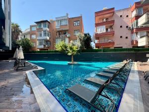 a swimming pool with lounge chairs in a building at C lounge cleopatra premium Apartment in Alanya