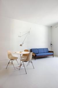 Habitación con mesa, sillas y sofá azul. en Concoct Milano, en Milán
