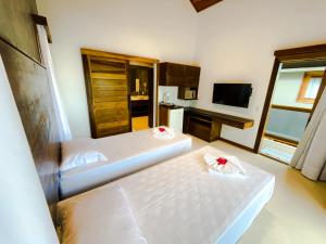 a hotel room with two beds and a television at Hura Vilas in Itarema
