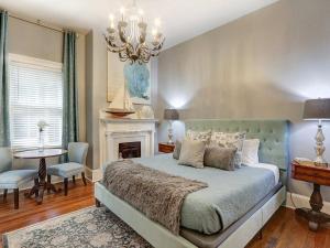 a bedroom with a bed with a fireplace and a chandelier at Southern Hall Lower in Savannah +19 photos