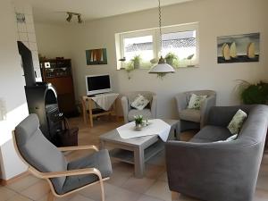 Una sala de estar con un sofá y sillas y una mesa. en Ferienhaus Poth, en Bübbens