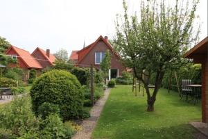 una casa con un patio con un árbol y una mesa en Ferienhaus Poth, en Bübbens 3 fotos más
