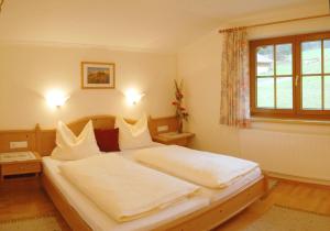 une chambre avec un lit avec des draps blancs et une fenêtre dans l'établissement Appartmenthaus Geroldhof, à Ramsau am Dachstein