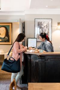 two women standing at a counter in an office at Hôtel Le Relais de Poste Arles Centre Historique in Arles