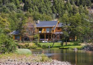 a log home with a river in front of it at Rio Hermoso Hotel De Montaña in San Martín de los Andes