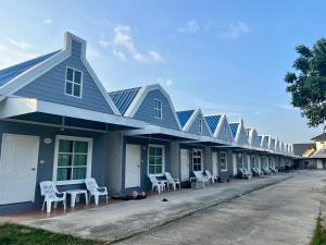 a row of houses with white chairs on a street at Preme village in Ubon Ratchathani