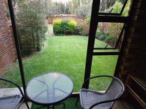 Una mesa y sillas en un porche con vista a un patio. en Blue Button, en Pretoria