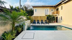 a swimming pool in front of a house at Pousada Pantai Maresias in Maresias