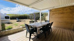 a wooden deck with a table and chairs on it at Charmante location au pied des dunes in Sainte-Marie-de-Ré