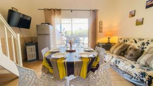 a dining room with a table and a couch at Charmante location au pied des dunes in Sainte-Marie-de-Ré