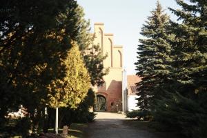 a church with trees in front of a building at Nostra Cultura Zamek Bierzgłowski in Zamek Bierzgłowski