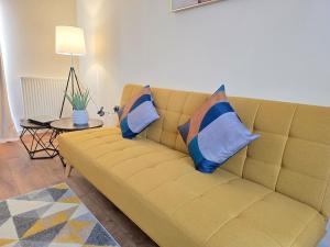 a yellow couch with pillows in a living room at Family-Friendly 4-Bed Swansea Stay with Parking in Landore