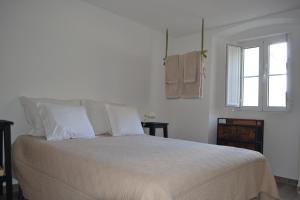 a bedroom with a bed with white sheets and a window at Casa Aurora in Escusa