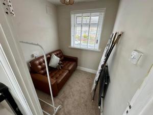 ein Wohnzimmer mit einem braunen Ledersofa und einem Fenster in der Unterkunft Comfortable 2-Bed Home near Swansea Bay in Morriston