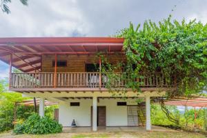 a house with a balcony and a tree at Casa Quetzal in San Luis