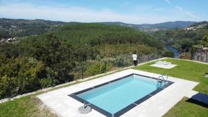 a man standing on top of a hill with a swimming pool at Casa do Barbeiro - View of the River Minho in Melgaço