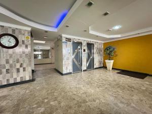 a lobby with a clock and a yellow wall at Pé na areia em Nova Mirim com Wi-Fi e conforto! in Samaritá