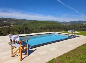 a swimming pool with a chair sitting next to it at Casa do Barbeiro - View of the River Minho in Melgaço
