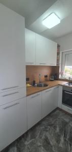 a kitchen with white cabinets and a sink at Apartman Katić in Odžak