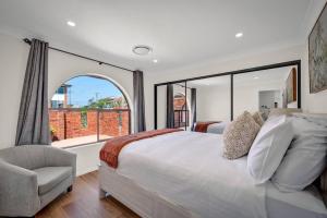a bedroom with a bed and a window and a chair at Sienna Arches - Modern Family Haven near Ocean Baths in The Entrance