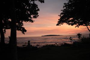 a person sitting on the beach at sunset at Pondok Wisata Karapyak Jajapin in Nusa Were +7 photos