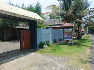 a sign in front of a building with a palm tree at Pondok Wisata Karapyak Jajapin in Nusa Were
