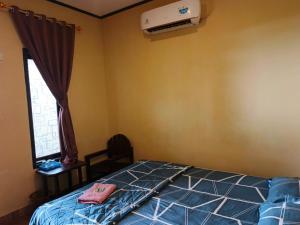 a bedroom with a bed and a window and a air conditioner at Pondok Wisata Karapyak Jajapin in Nusa Were