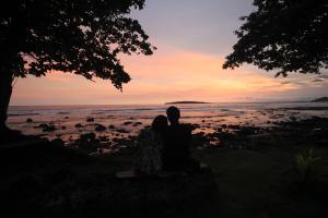 a couple sitting on a bench watching the sunset at Pondok Wisata Karapyak Jajapin in Nusa Were
