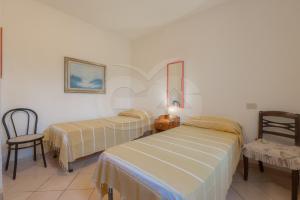 a hotel room with two beds and a chair at La Casina a Schiopparello - Goelba in Portoferraio