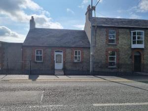 a brick house with a fence in front of a street at Adare House Newbridge in Newbridge