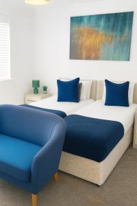 a bedroom with two beds and a blue couch at Harry Potter Stay with Watford & London Links - Family house in Abbots Langley