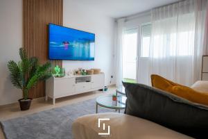 ein Wohnzimmer mit einem Sofa und einem Fernseher an der Wand in der Unterkunft Wolfie Home Villacosta in Orihuela