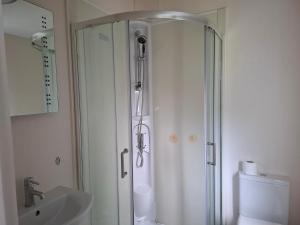 a white bathroom with a shower and a sink at Woodland Lodge - 2 Bedroom Spacious Lodge Sleeps 4 in Hastings +8 photos
