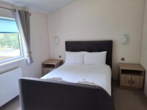 a bedroom with a bed with white sheets and a window at Woodland Lodge - 2 Bedroom Spacious Lodge Sleeps 4 in Hastings