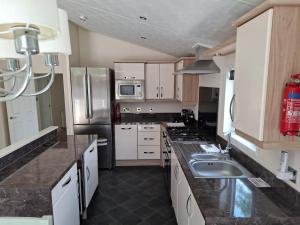 a kitchen with white cabinets and stainless steel appliances at Woodland Lodge - 2 Bedroom Spacious Lodge Sleeps 4 in Hastings