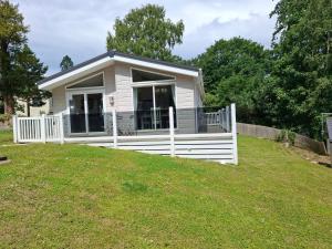 a small white house with a white fence at Woodland Lodge - 2 Bedroom Spacious Lodge Sleeps 4 in Hastings