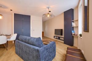 a living room with a blue couch and a tv at Pont de Peira - 2.5 km dAgen in Le Passage