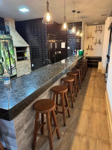 a bar with a row of stools in a restaurant at Rooftop Studio Premium in Bom Despacho