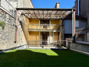 a house with a balcony and a yard with green grass at A l'ombre de la Tour in Lourdes