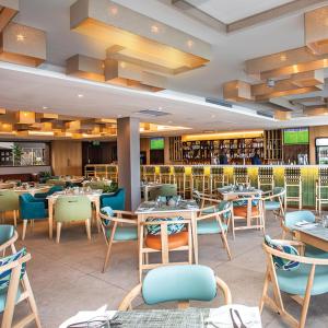 a restaurant with tables and chairs and a bar at Lagoon Beach Hotel & Spa in Cape Town