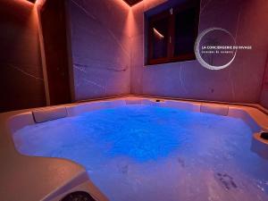 a large tub with blue water in a room at Chalet neuf La Marmotière - Vue sur la Montagne in Combloux